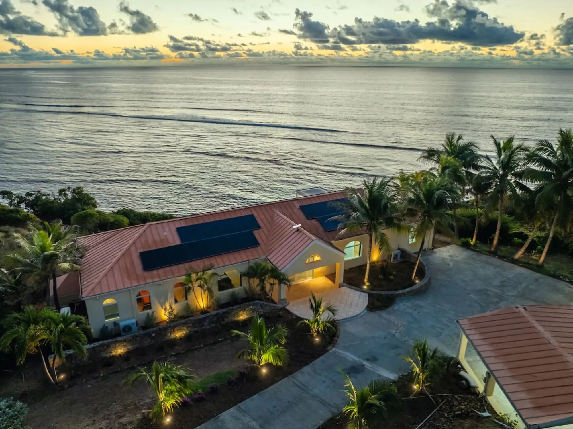 The villa and pool lit at dusk, seen from the air