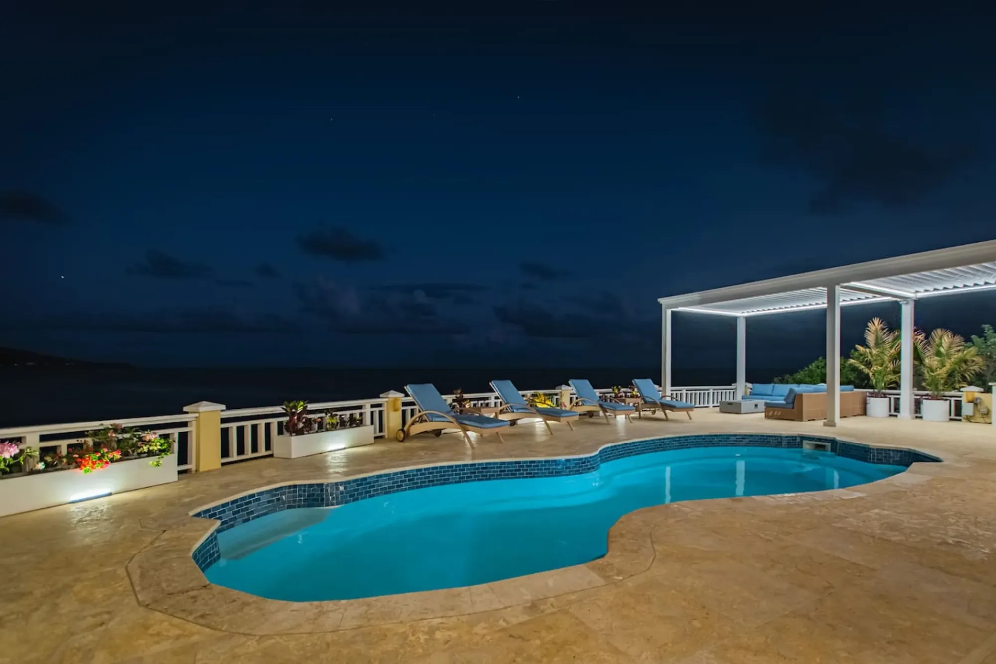 The pool deck lit at dusk above the ocean